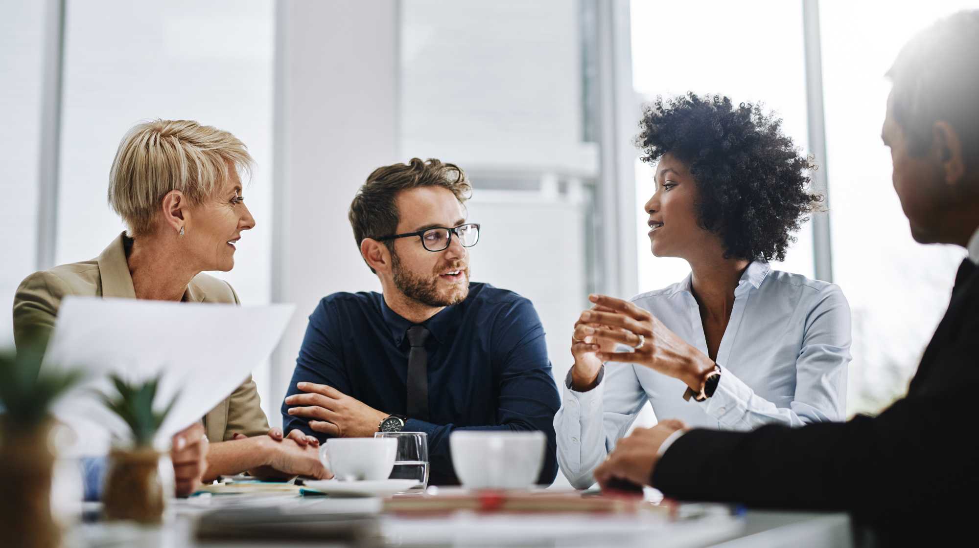 Woman speaking team sitting at table together, close, black, white, tan